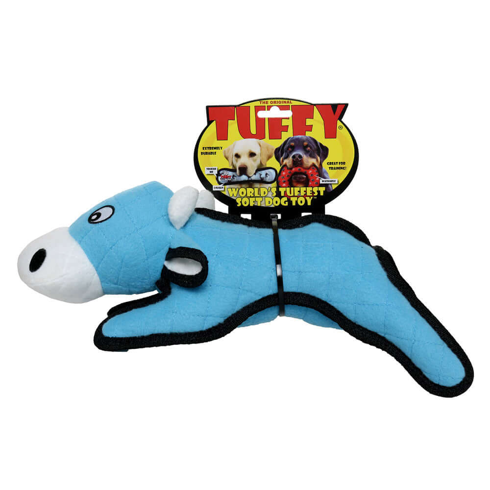 Blue plush cow-shaped dog toy with a white muzzle and black trim, marketed as "Tuffy World's Tuffest Soft Dog Toy," shown in its packaging.