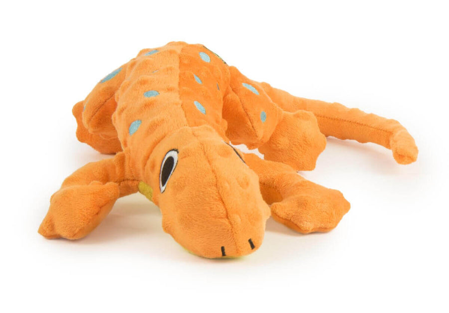 Orange plush lizard-shaped dog toy with black and white eyes, blue spots, and a yellow underside, laying flat, ideal for interactive play.