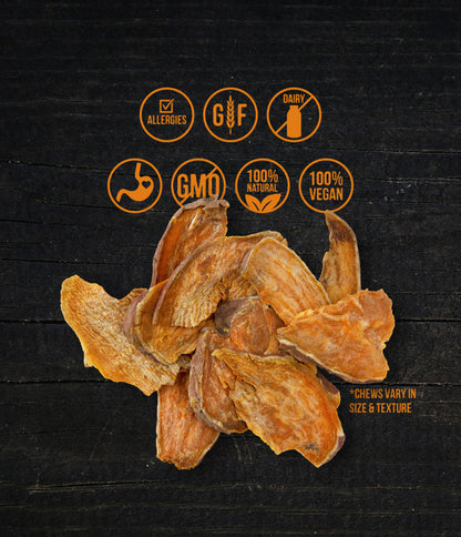 A display of dried sweet potato chews laid out on a dark surface. Above the chews, icons indicate various product attributes, including allergy-friendly, gluten-free, dairy-free, non-GMO, 100% natural, and 100% vegan. A note at the bottom right mentions that the chews vary in size and texture.