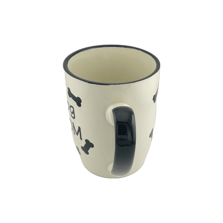 A small ceramic mug with a white base and black handle, featuring the text "dog dad" along with black bone shapes around the exterior. The design is simple and appealing to dog lovers, especially those who identify as dog moms.