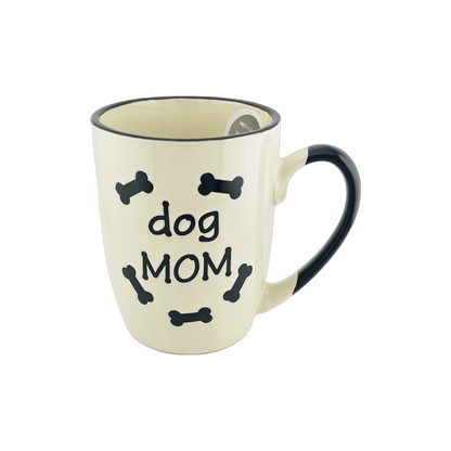 A small ceramic mug with a white base and black handle, featuring the text "dog MOM" surrounded by small black bone shapes. The design is simple and appealing, ideal for dog lovers, especially those who identify as dog moms.