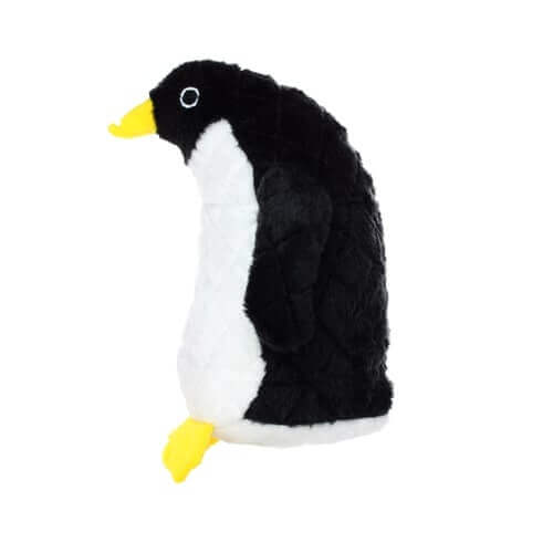 A side view of a plush penguin-shaped dog toy with a black back, head, and wings, a white belly, and yellow beak and feet. The toy features embroidered eye details and is designed for durable, interactive play.