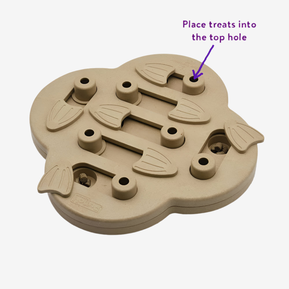 Top view of Nina Ottosson Hide N’ Slide dog puzzle toy showing labeled treat hole—sliding compartments reveal rewards as dogs play.