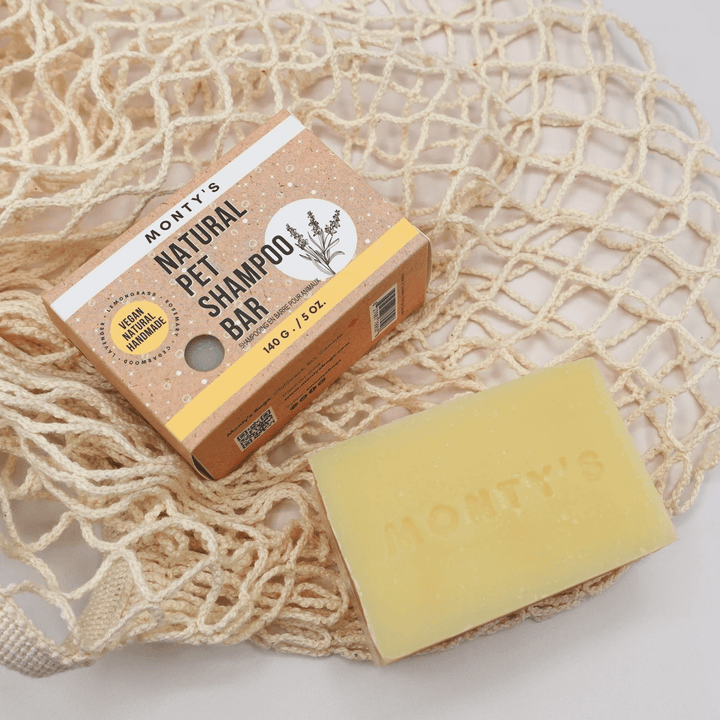 Monty's natural pet shampoo bar with vegan, handmade packaging and a yellow soap bar placed on a sustainable net background.