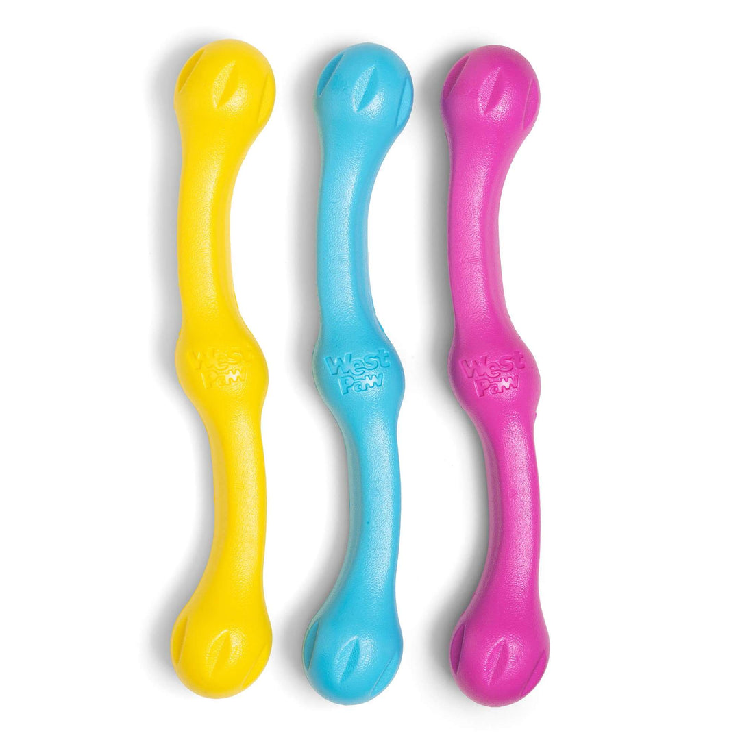 Three colorful dog toys in yellow, blue, and pink on a white background