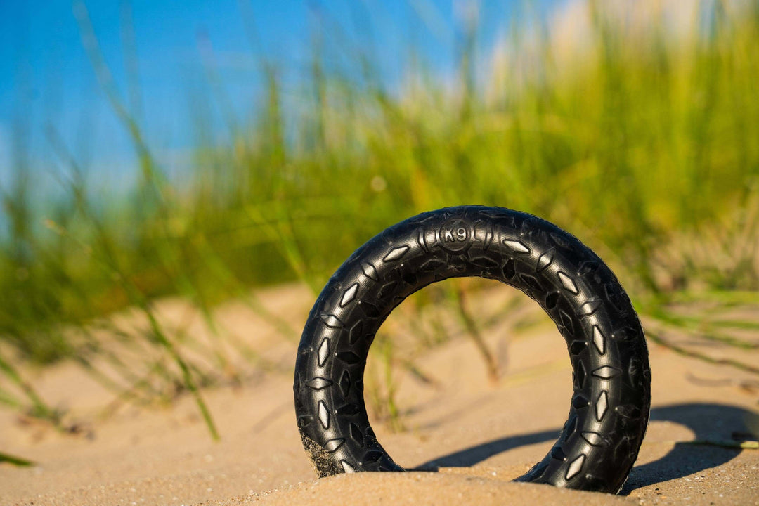Black tire on sand with grass in the background