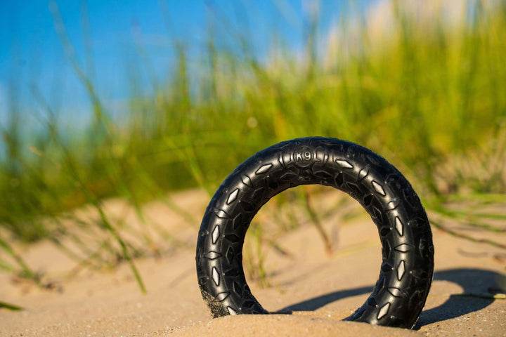 Black tire on sand with grass in the background
